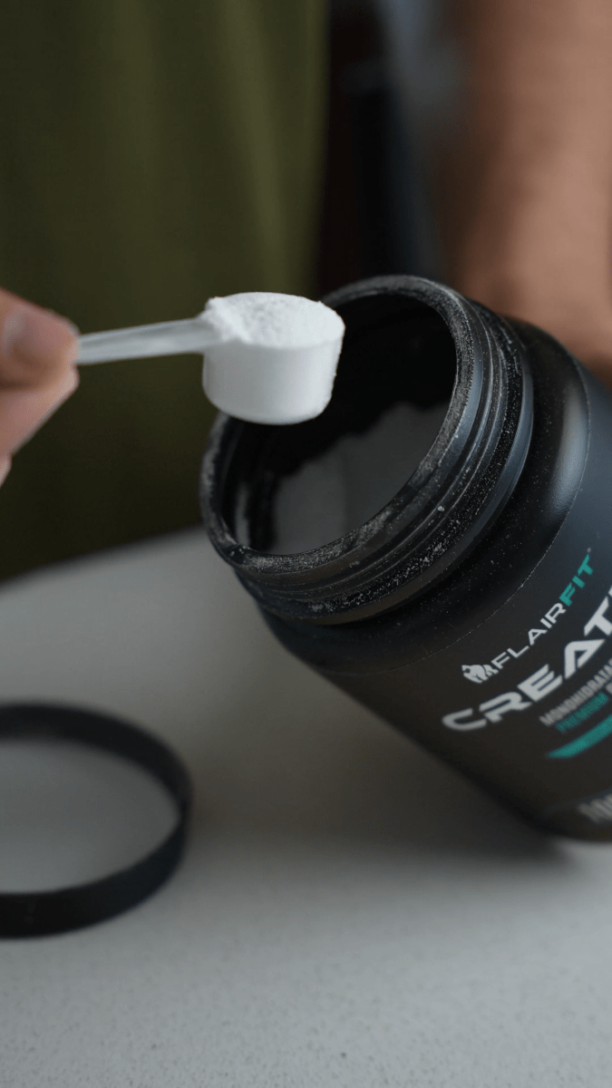 Scoop with creatine powder beside the FLAIRFIT Creapure 500 g container.